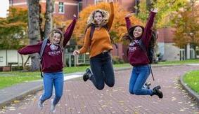 Three SPU student jump 和 laugh while in Tiffany Loop